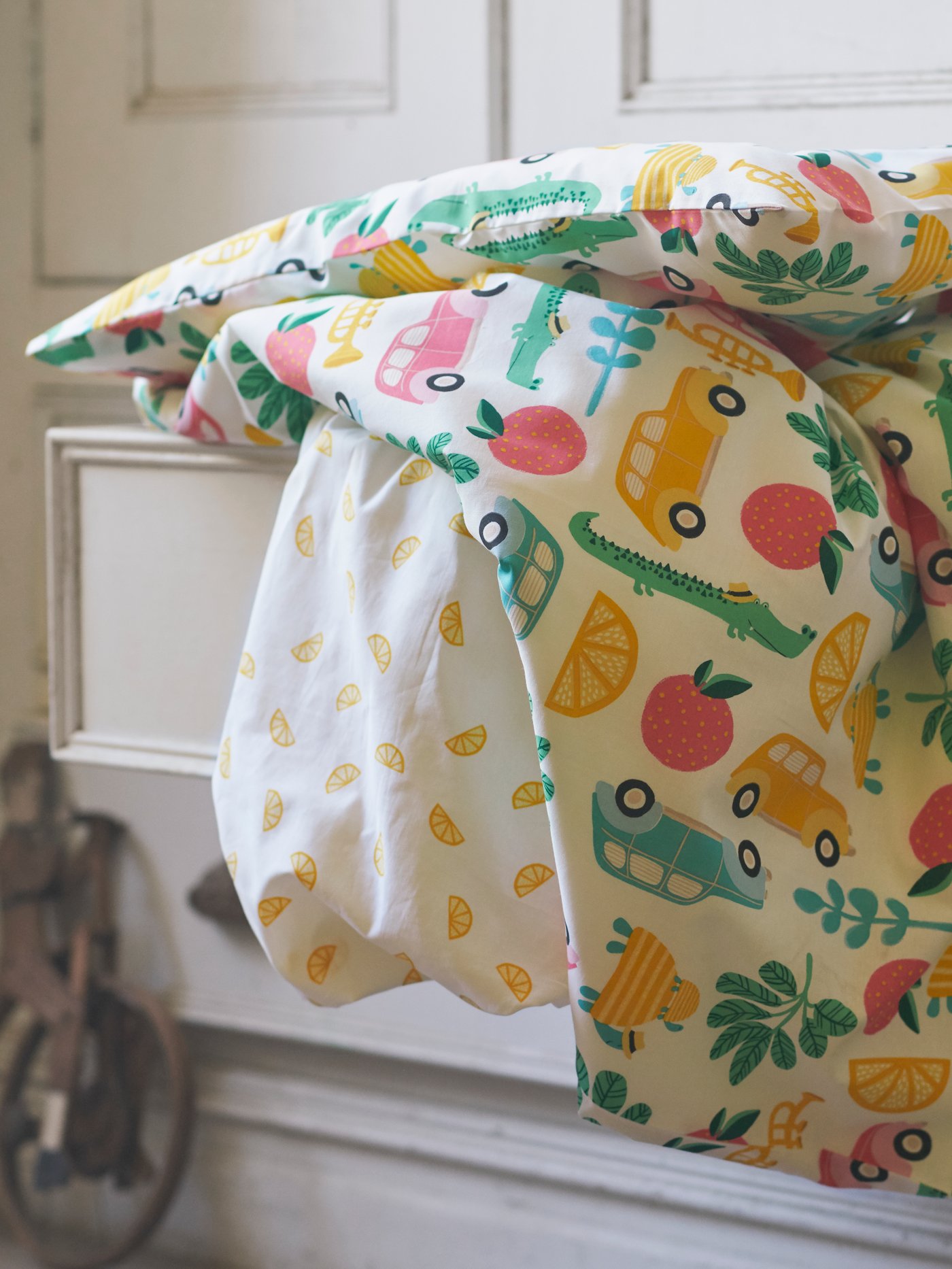 A close-up of RÖRANDE quilt cover and pillowcase with a colourful graphic print, placed on top of a pulled-out drawer.