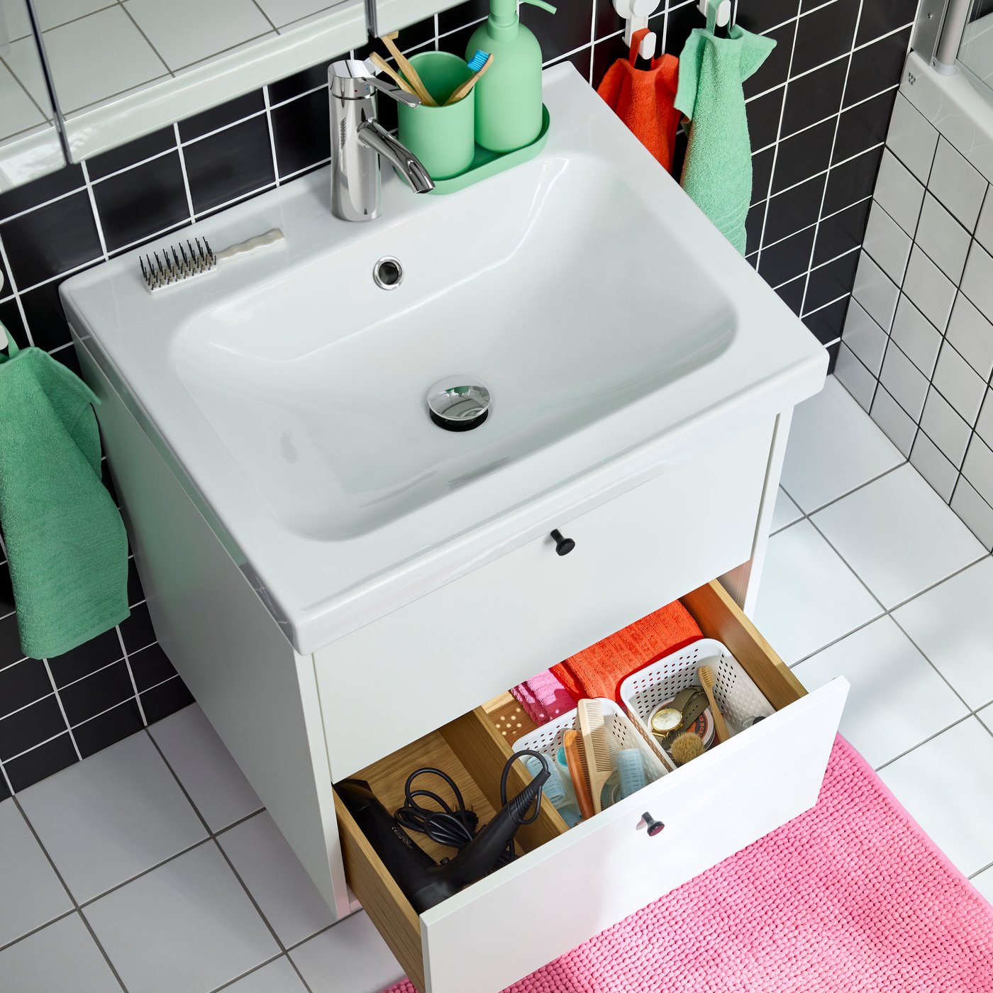 A white HAVBÄCK/ORRSJÖN washstand with two drawers. One is open and inside are small boxes in different sizes. White floor.
