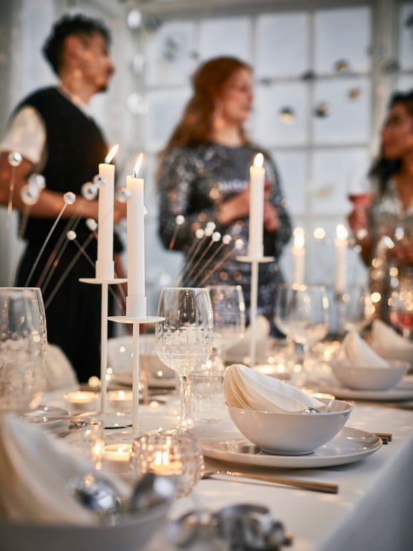 Mesa en blanco y plata con temática de Nochevieja con portavelas, cristalería, candelabros y servilletas de algodón FRÖJDA.