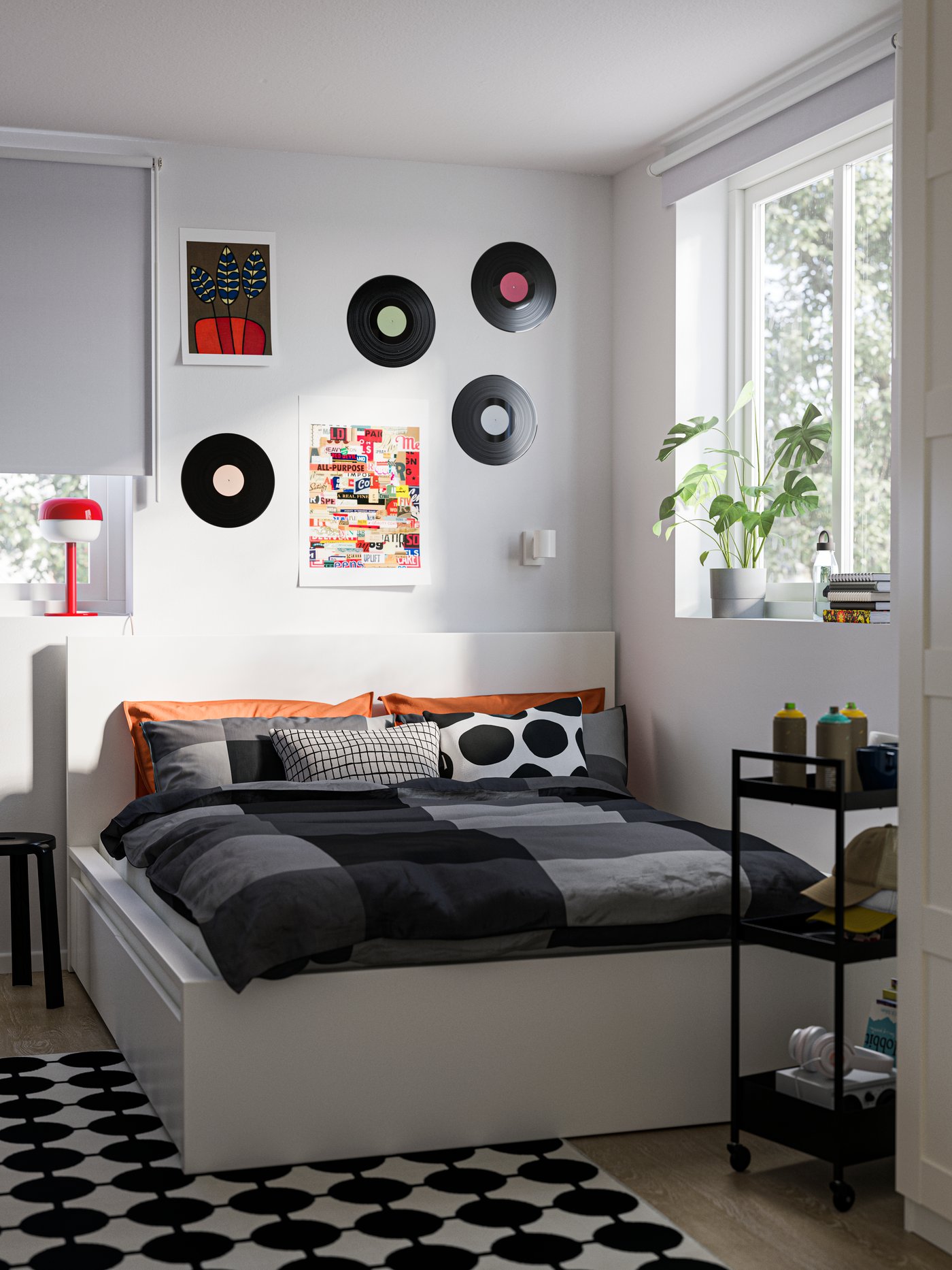 A corner of a bedroom with a MALM bed, a black/white VÄNDPLATS rug on the floor and old records on the wall above the bed.