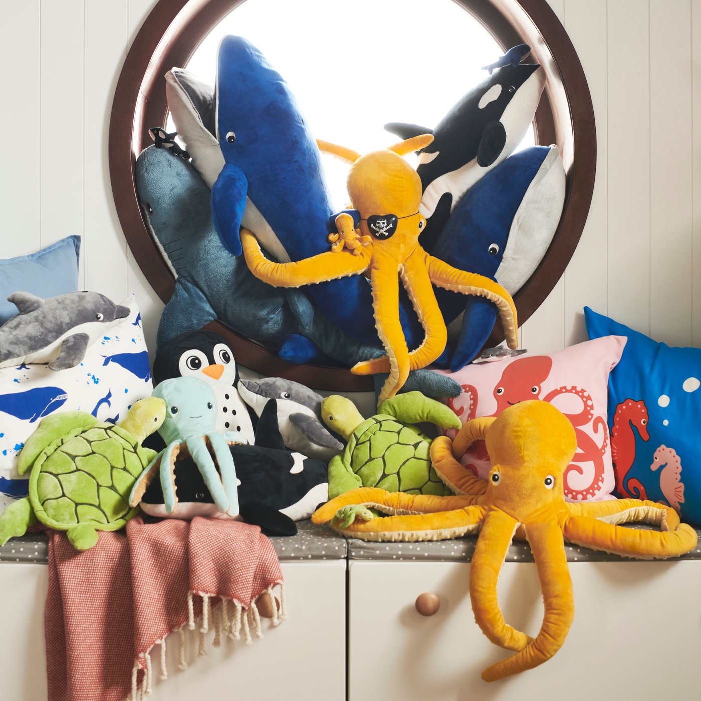 On a cabinet are ocean-inspired BLÅVINGAD soft toys that are made from a mix of recycled PET and ocean-bound plastic.