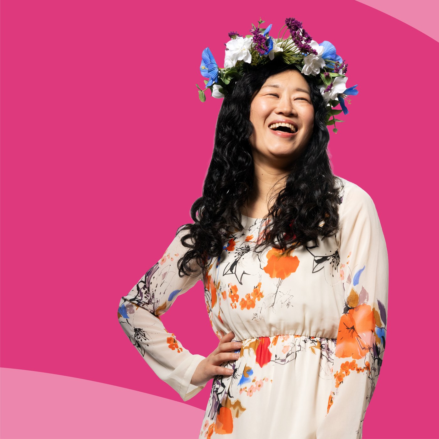 Een lachende vrouw heeft een bloemenkrans op haar hoofd.