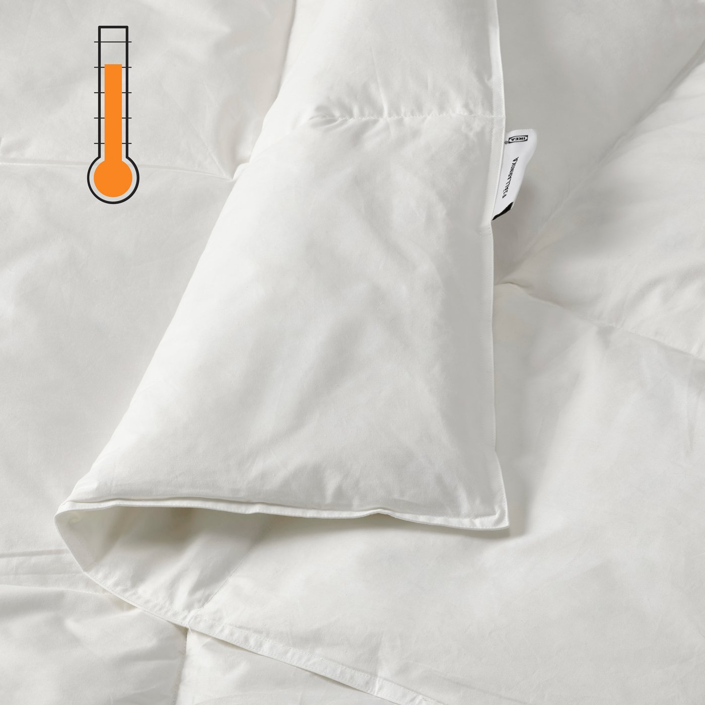 A close-up of a folded white duvet with an organge warm temperature symbol in the top left corner.