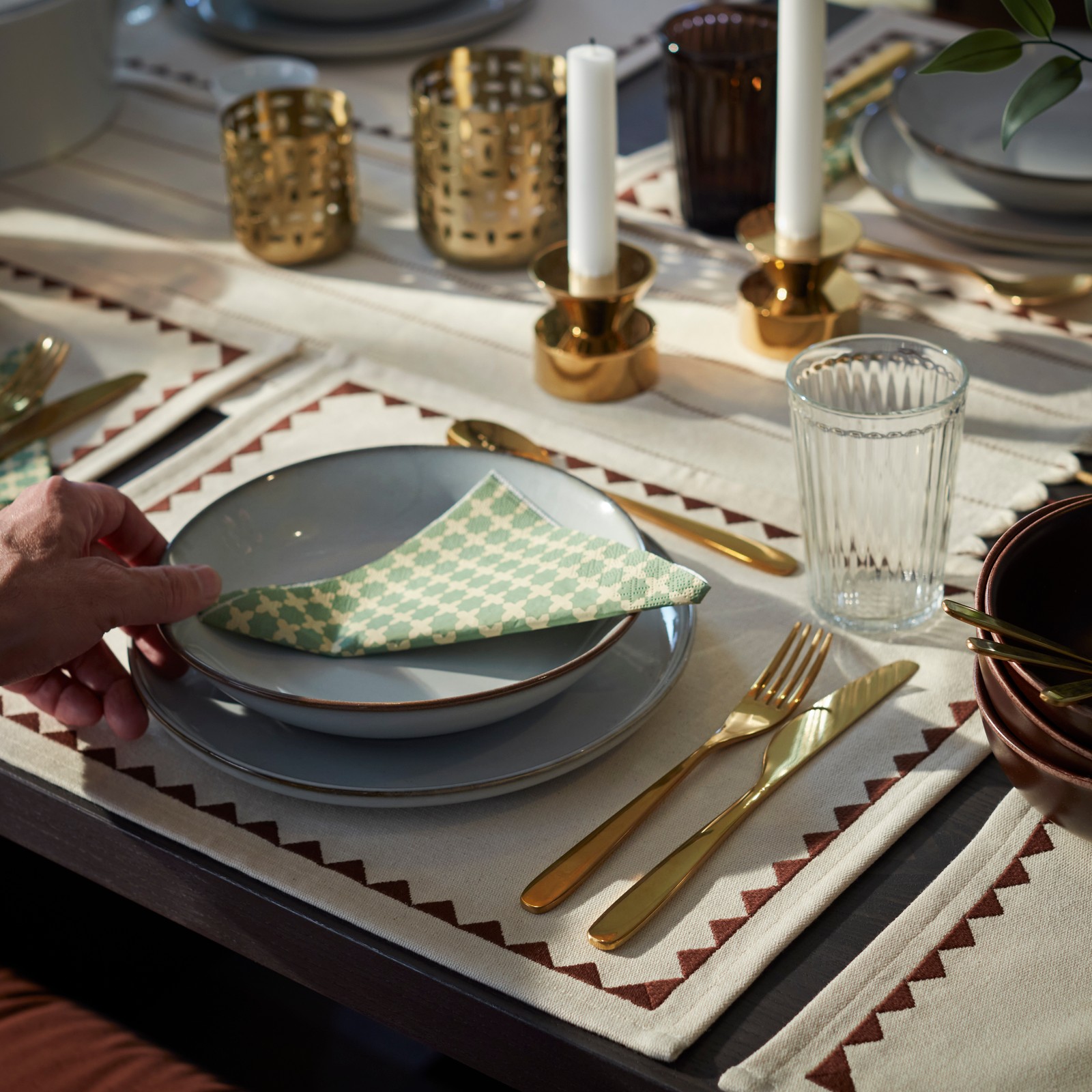 A beautifully set dining table, with a green GOKVÄLLÅ paper napkin and an ornamented textile GOKVÄLLÅ placemat.