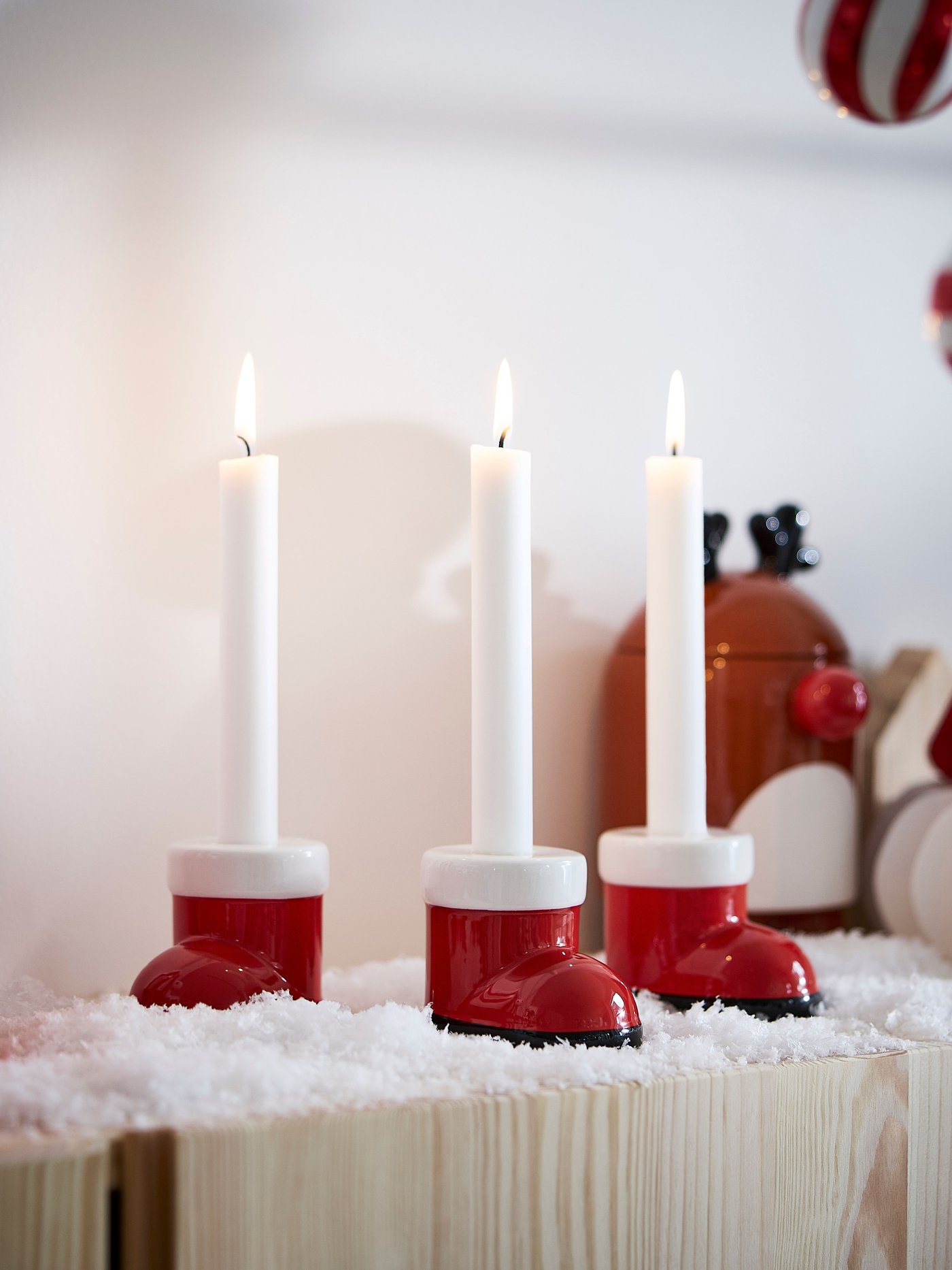 Ein rot-weißer VINTERFINT Kerzenhalter in Form eines Weihnachtsmannstiefels.
