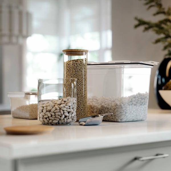 Frasco EKLATANT con tapa, lleno de frijoles, colocado sobre una superficie de cocina junto a otros recipientes transparentes para alimentos.
