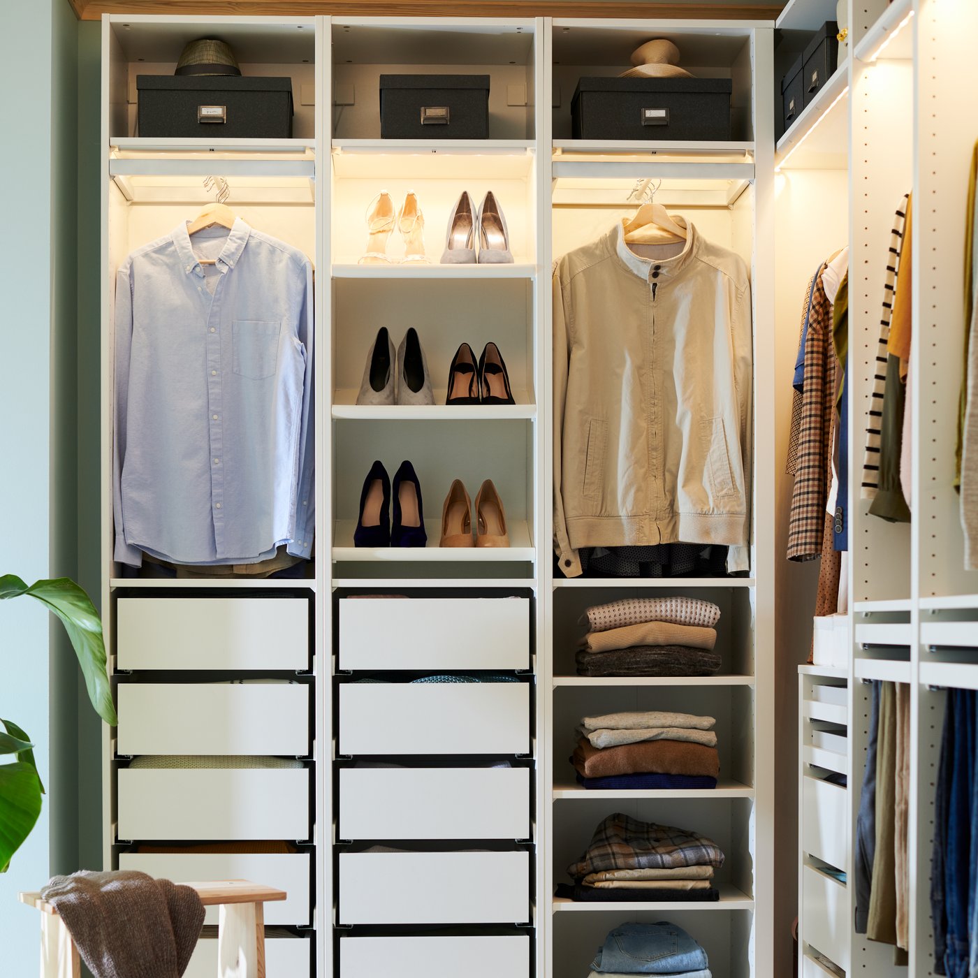 An open PAX system, with integrated lighting, showing off hanging shirts, neatly folded sweaters and shoes put on display.