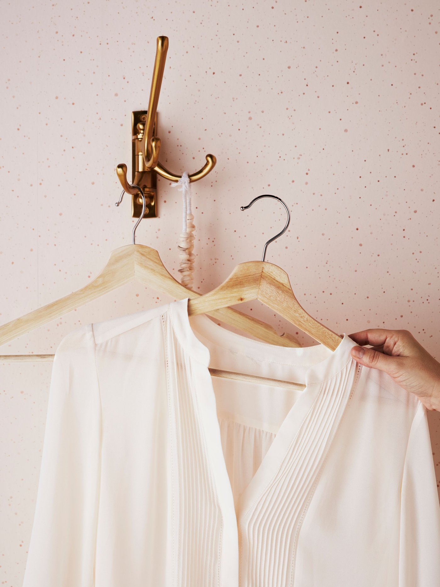 Ein BUMERANG Kleiderbügel wird an einen Haken gehängt.
