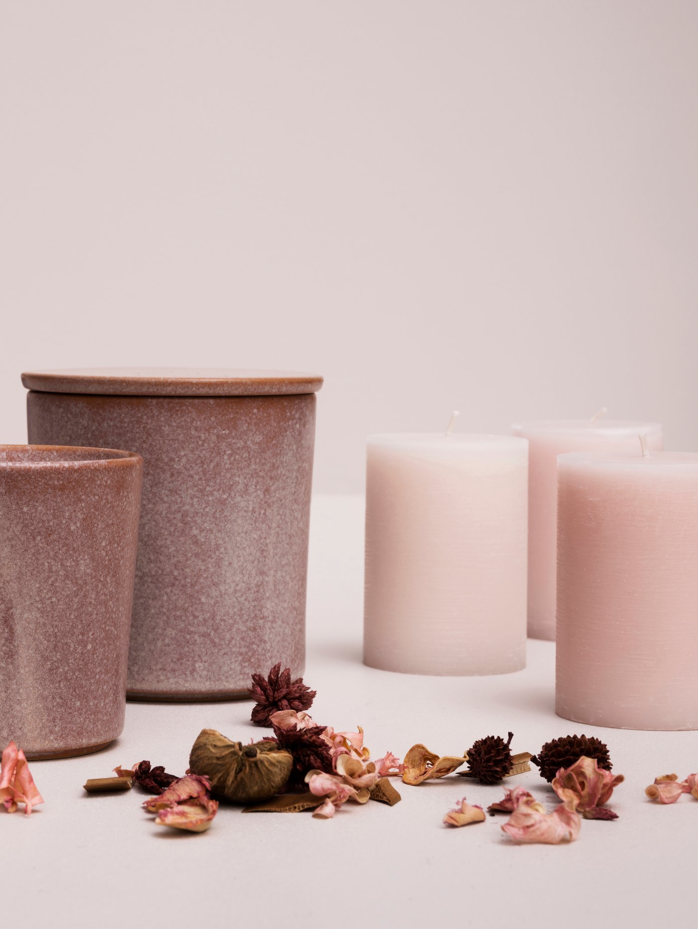 A collection of pink candles arranged on a table next to potpurri.