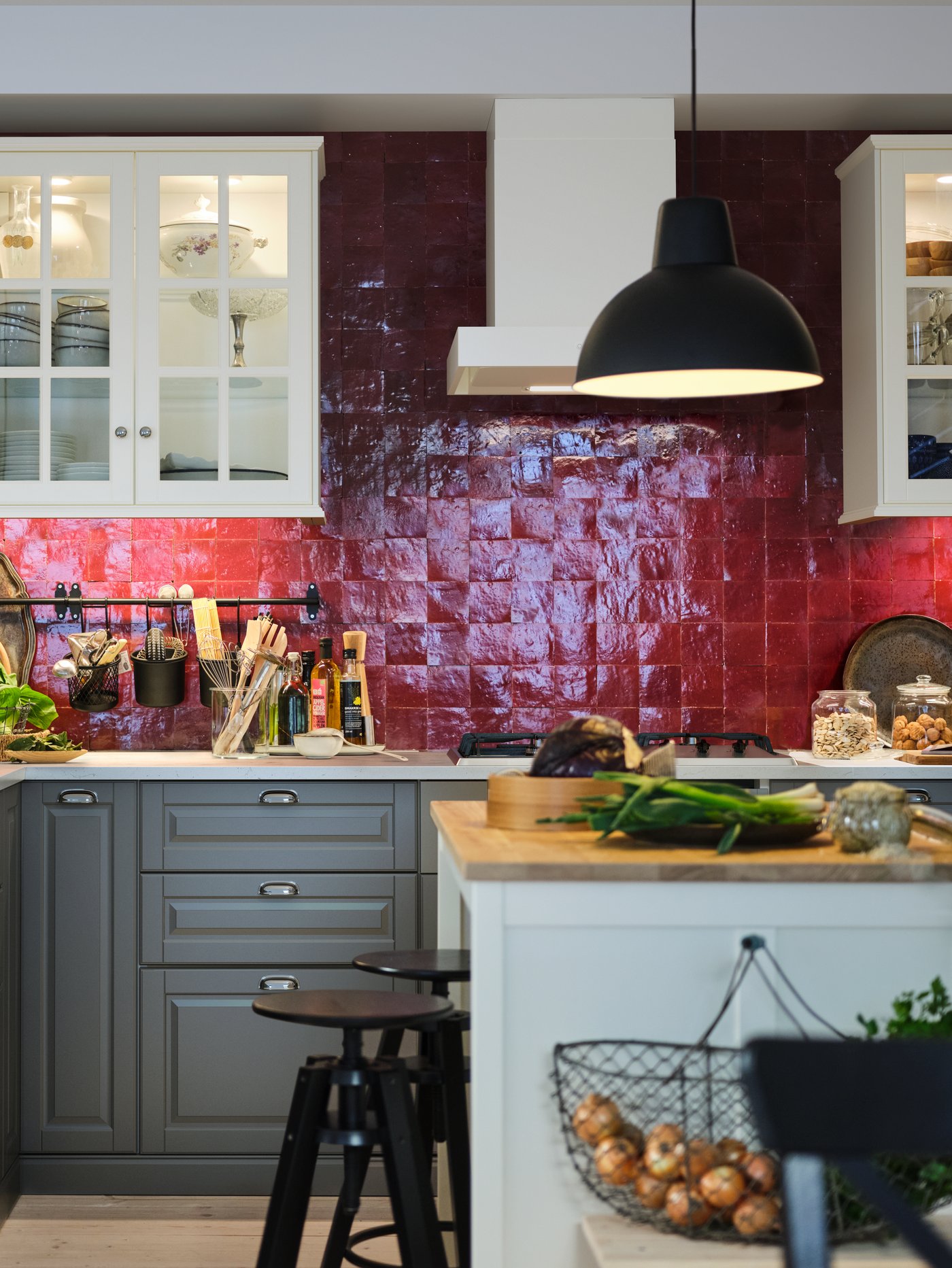 Una cocina con un armario bajo gris para fregadero con 3 frentes, 2 cajones y amortiguadores integrados, detrás de una isla de cocina.