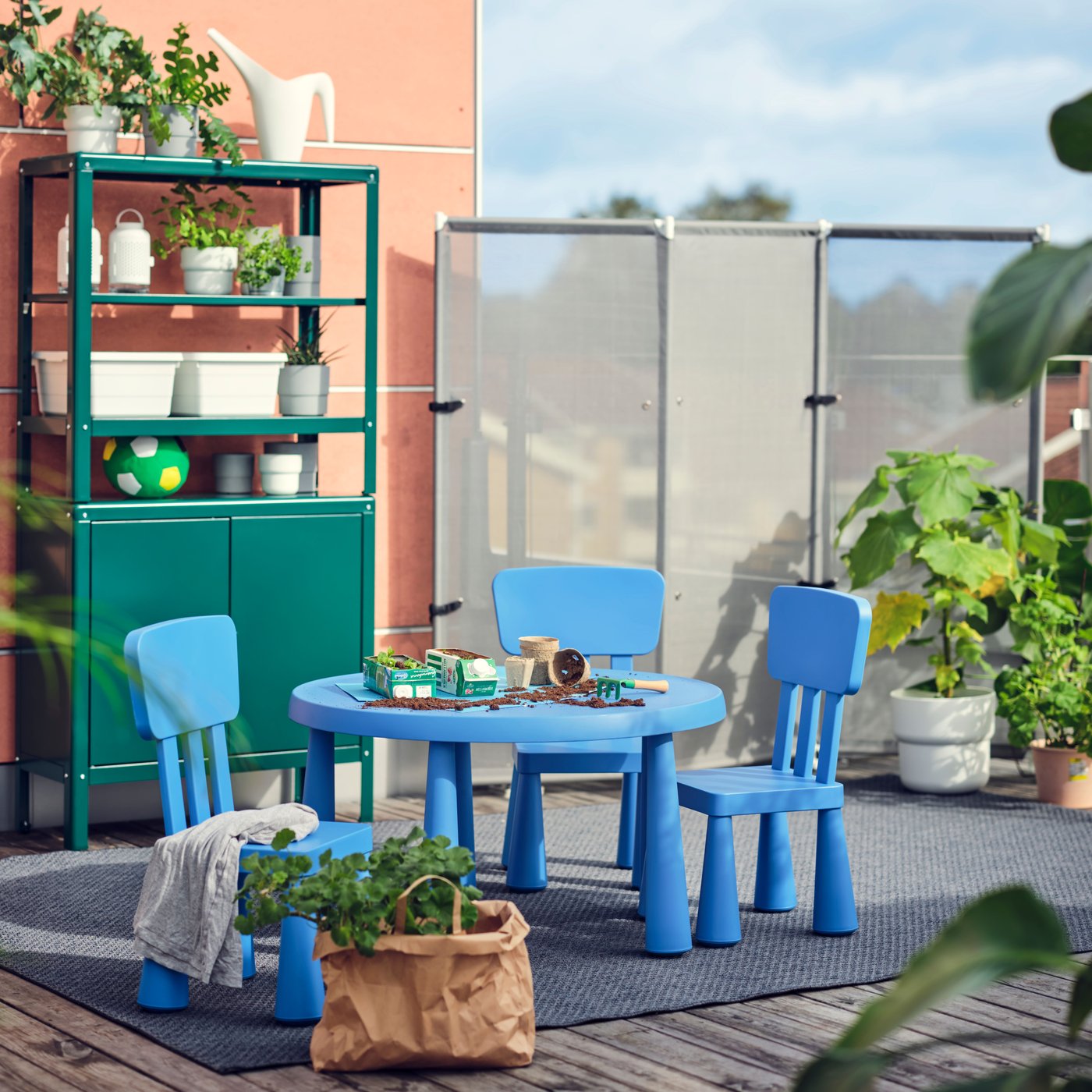 Sillas infantiles MAMUT en color azul, colocadas alrededor de una mesa a juego en un espacio exterior.