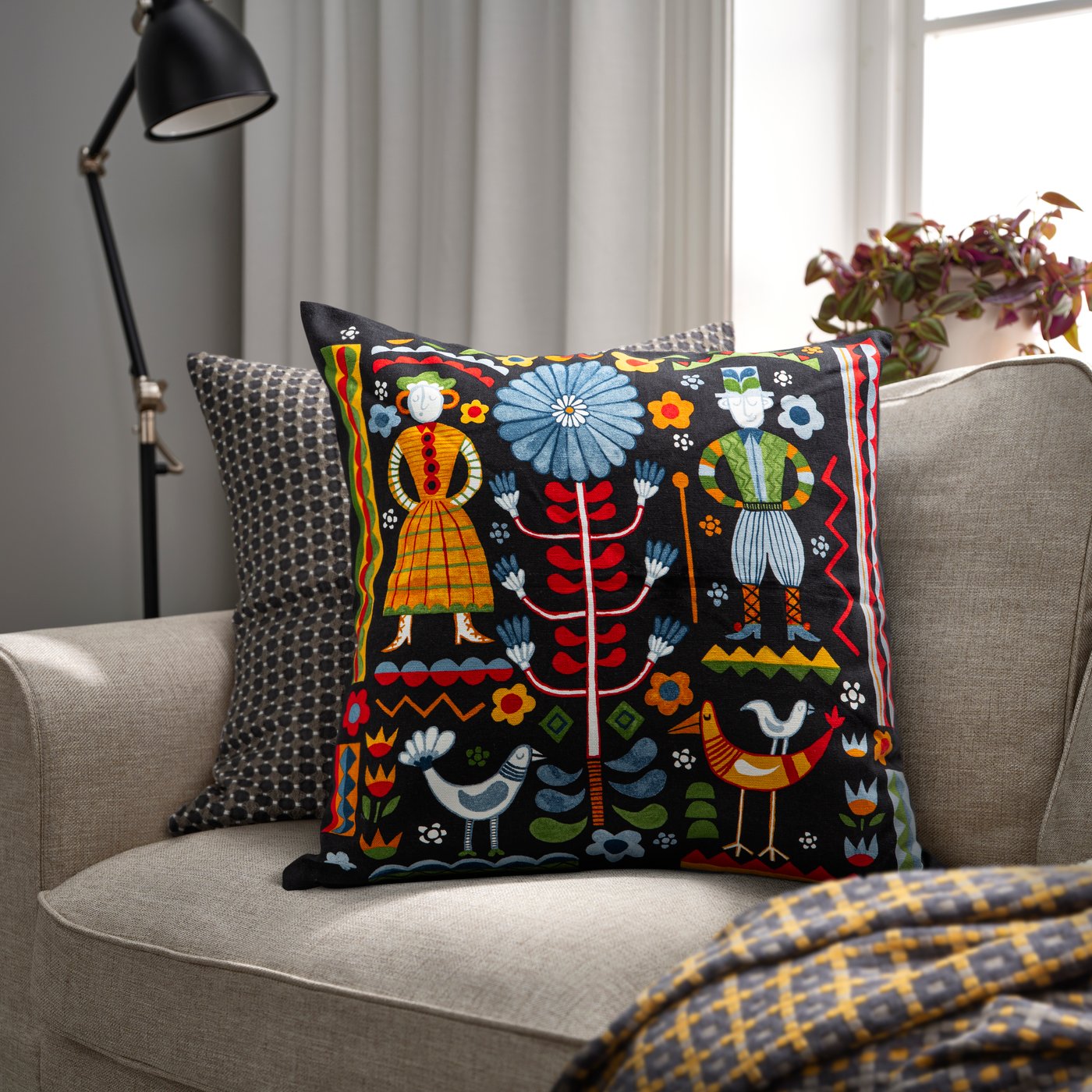 A pillow with bright patterns is propped up on a beige couch.
