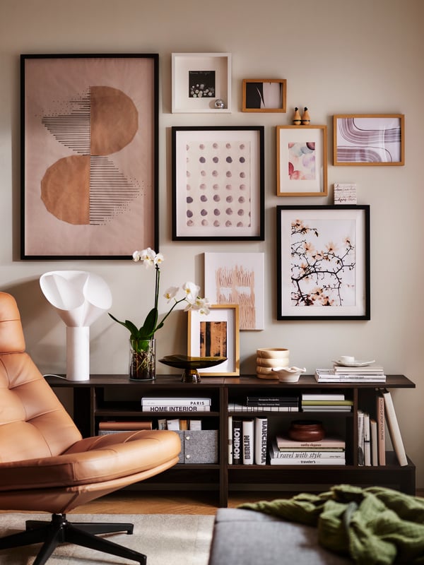 Part of a bright living room with a golden-brown HAVBERG swivel armchair, HOLMERUD side tables and a cluster of framed art.