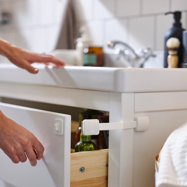 Seguro para cajones UNDVIKA color blanco, en un mueble de baño.