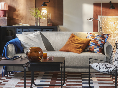 A living room features an Öreryd grey-beige SALTMYRAN 3-seat sofa placed in front of a coffee table and on a MARKBLÅMME modern rug.