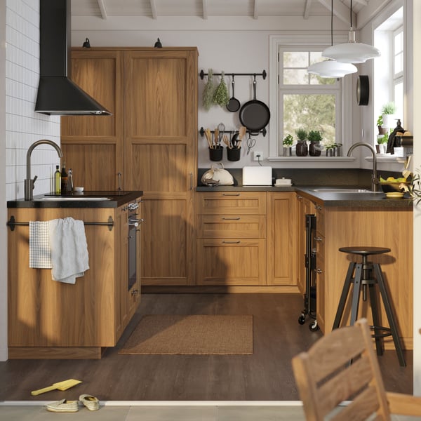 Una cocina con muebles efecto madera y una alfombra frente al lavaplatos.