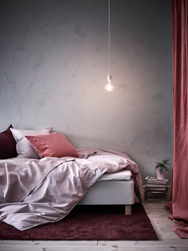 A bed with an open quilt hanging over the bed frame and several pillows