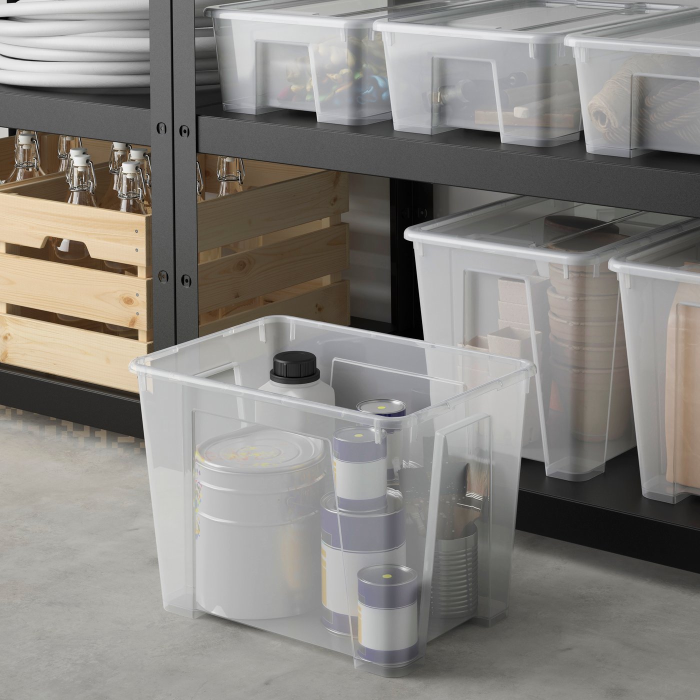 Eine SAMLA Kiste mit Inhalt steht vor einem Regal.