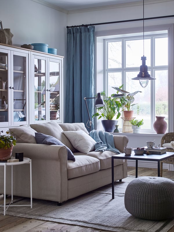 Una sala con un sofá de dos cuerpos y dos librerías HEMNES con puerta de vidrio.