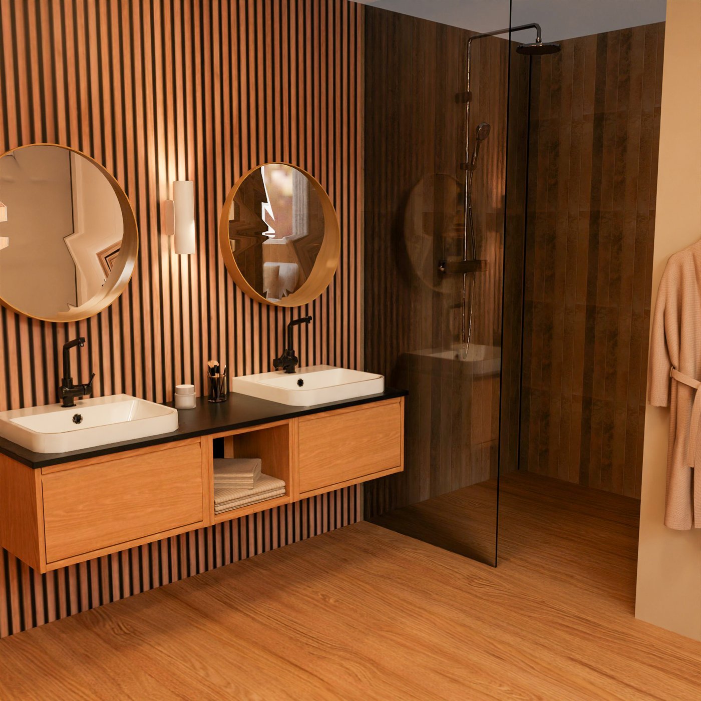 Teil des Badezimmers eines Hotelzimmers. Blick auf einen Doppelwaschtisch, darüber zwei runde Spiegel. Neben dem Waschtisch eine begebare Dusche mit Glastrennwand.