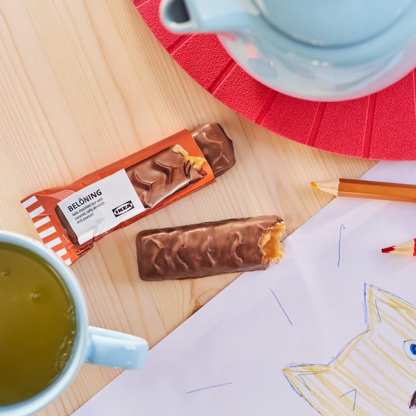 IKEA BELÖNING Schokoriegel auf Holzplatte mit Tee und Buntstift – süße Belohnung beim Entspannen oder Lernen zu Hause


