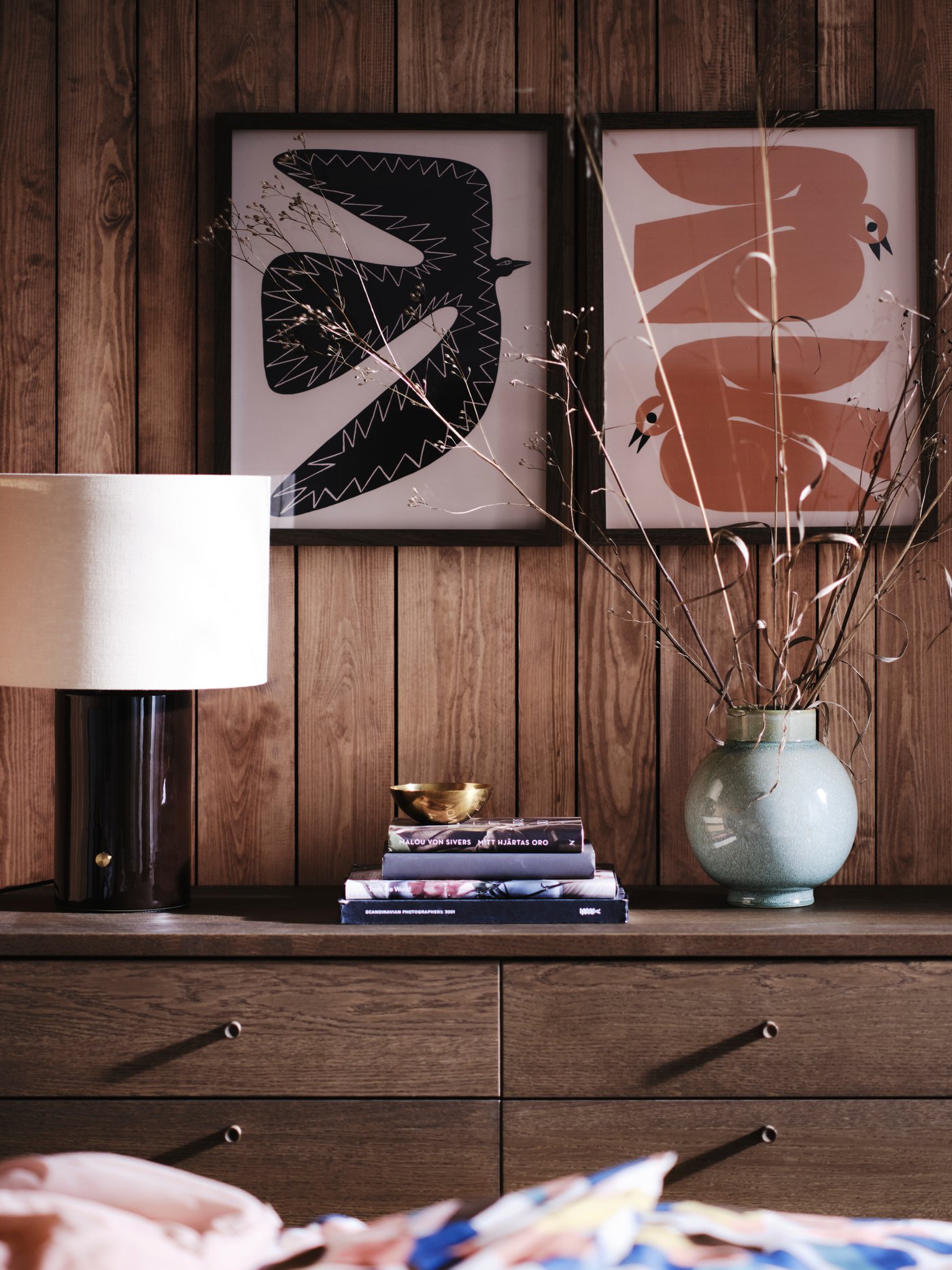 A HALGATT table lamp with a dark brown ceramic base and beige fabric shade on a brown chest of drawers.