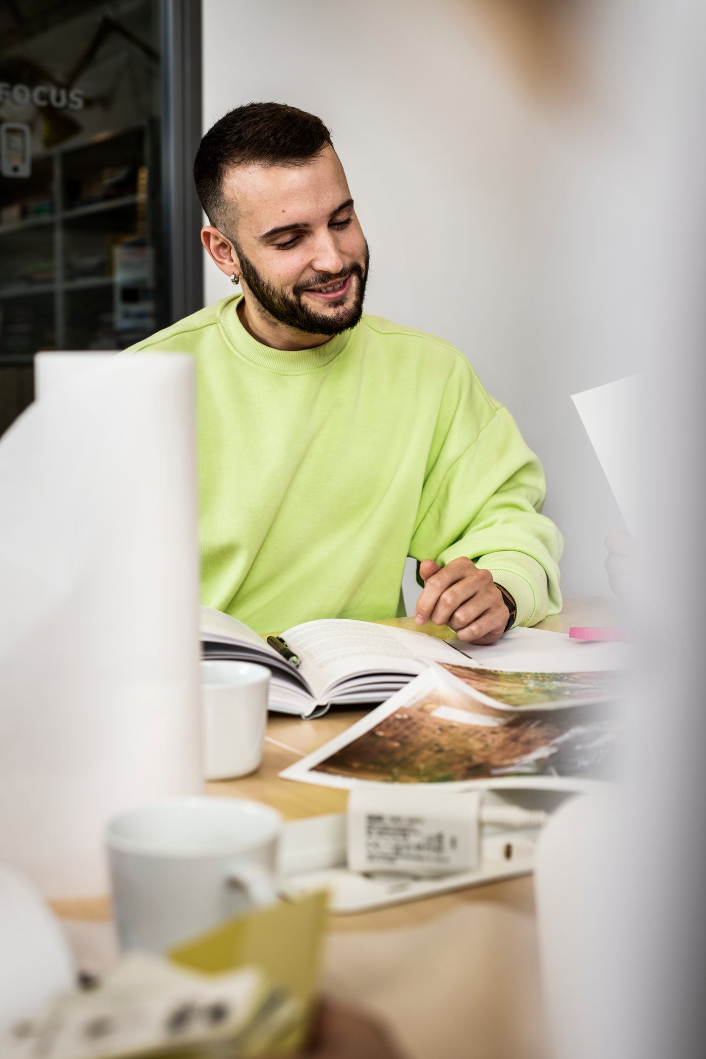 Mężczyzna w limonkowej bluzie siedzi przy biurku.