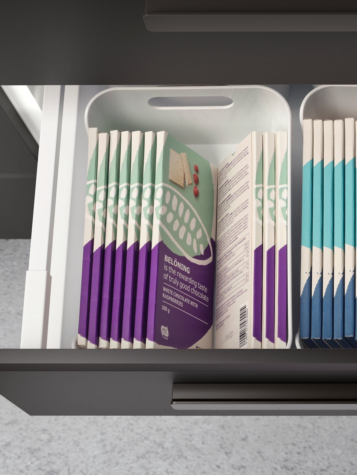 Laci dapur yang ditarik keluar menampakkan bar coklat BELÖNING yang tersusun kemas di dalam kotak VARIERA.