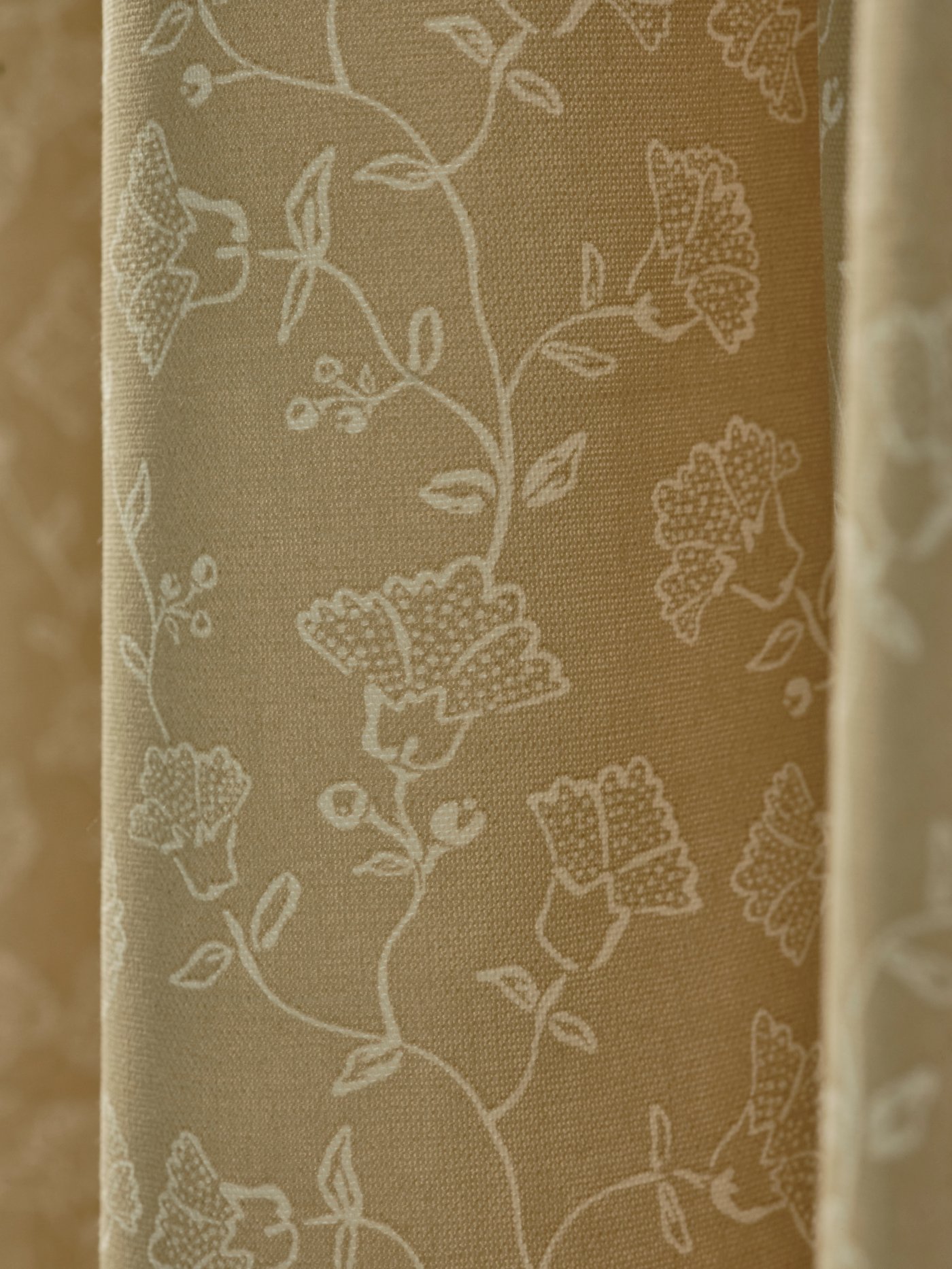 طيات ملفوفة وتفاصيل ستائر TRYSTÄVMAL بها نقوش ورود باللونين الأبيض والبيج.