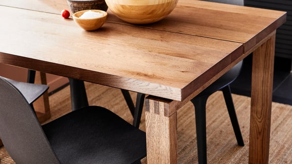 Blick von oben auf einen Holztisch, geölt, mit wunderschönen Details, daneben steht ein Stuhl