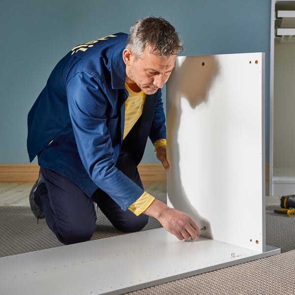 An IKEA co-worker assembling an IKEA piece of furniture.