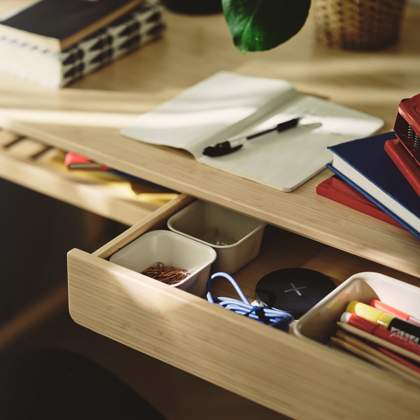 A close-up of a beige NOJIG organiser made from plastic, holding various stationery items in a drawer.