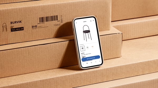 A phone with the IKEA app open is on a step IKEA packages of the BURVIK side table. In the app the BURVIK side table is open.