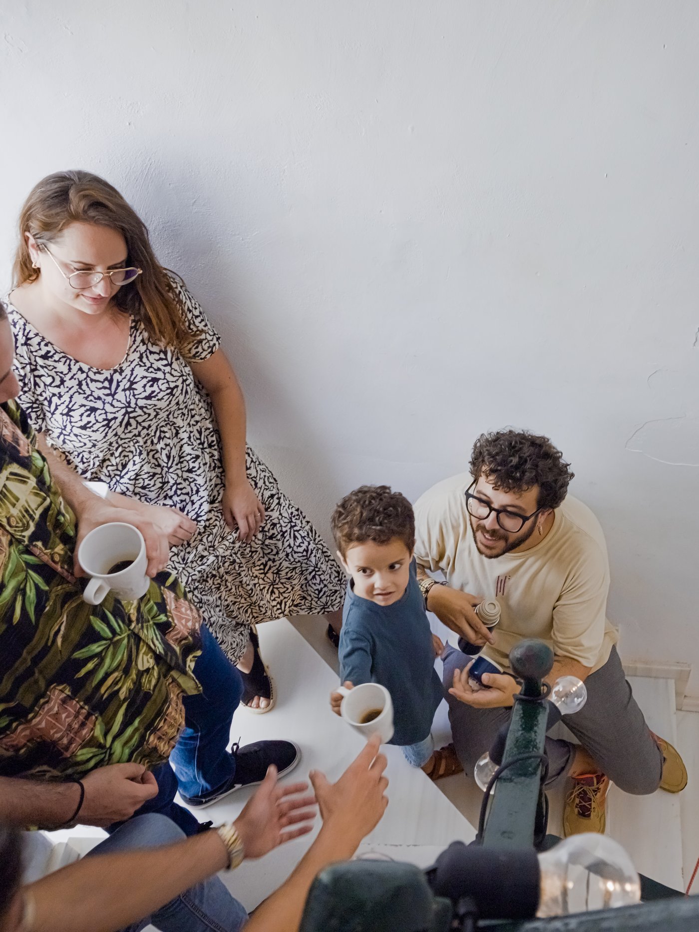 Un groupe de voisins boit du café dans des tasses FÄRGRIK, dans les escaliers d’un immeuble résidentiel.
