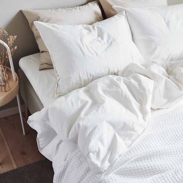Literie ÄNGSLILJA blanche sur un lit avec des oreillers.