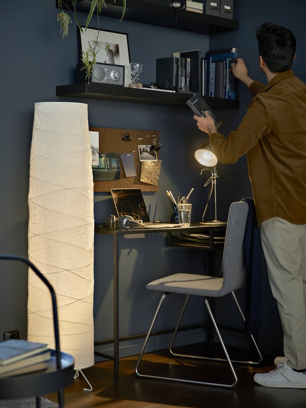 A compact workspace formed by a black-brown VITTSJÖ laptop table and a VOLFGANG chair, with wall-mounted LACK shelves above.