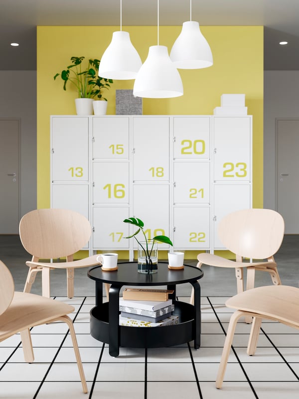 Four FRÖSET chairs in light wood and a black coffee table, two mugs and a plant, creating a relaxing zone in the office.