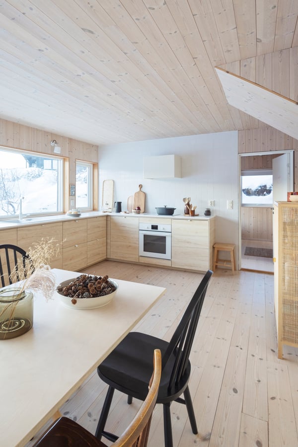 Et lyst kjøkken i bakgrunnen med spisebord foran.