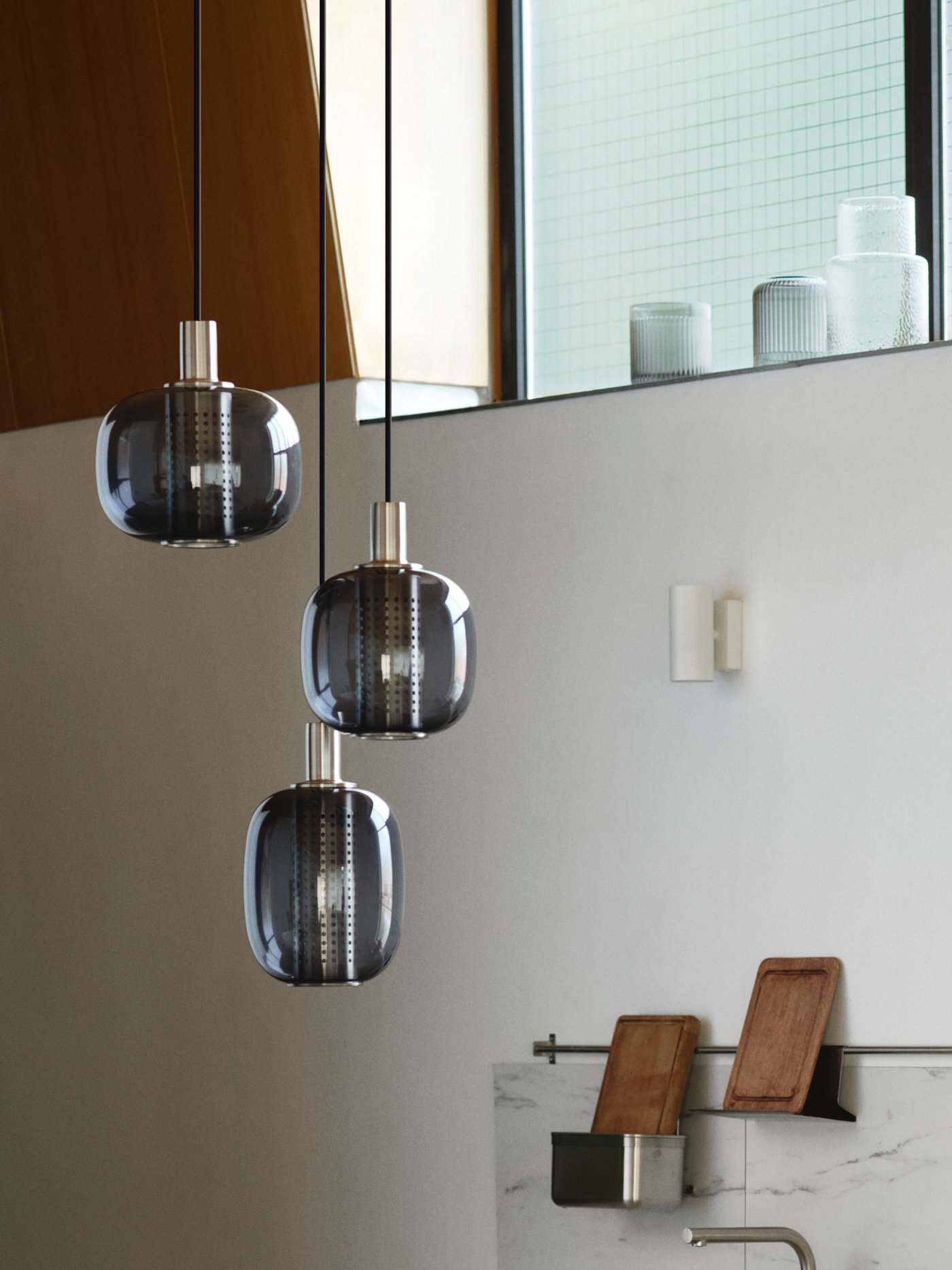 En HÖGVIND pendellampa i nickelplätering/grått glas med tre lampor.