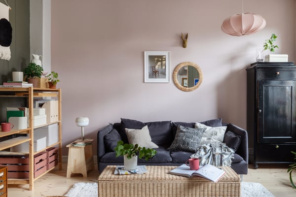 En grå sofa i en dus rosa stue med masse bra oppbevaring.