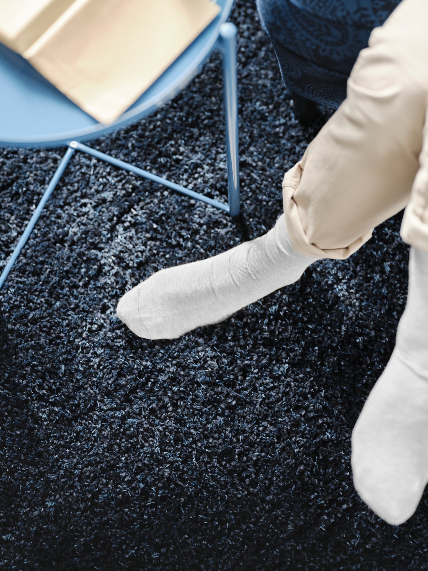 Et blått GLADOM brettbord i stua på et VOLLERSLEV teppe.