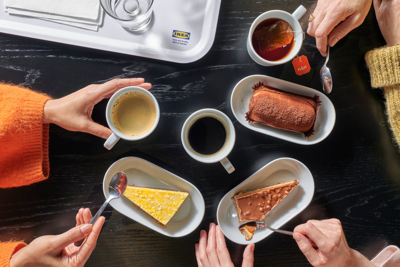 Vista dall'alto di una tavola al ristorante IKEA, con persone che assaggiano dolci e bevande calde