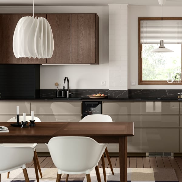 A white kitchen has base cabinets with high-gloss dark grey-brown VOXTORP fronts and wall cabinets with brown SINARP fronts.