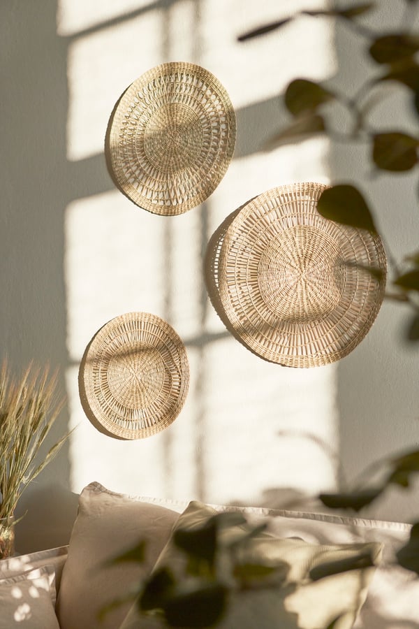 Drie handgemaakte zeegras GILLSTAD placemats als wanddecoratie aan een muur met veel zonlicht.