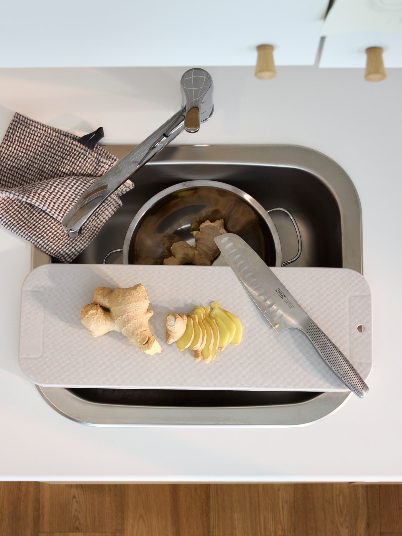 Grifería LAGAN con lavaplatos con una tabla de cortar encima.