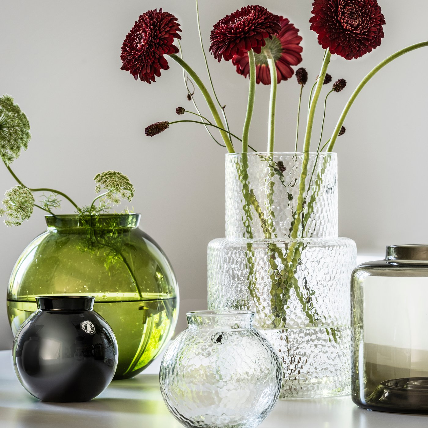 KONSTFULL vases in glass with flowers on a white table in bright room.
