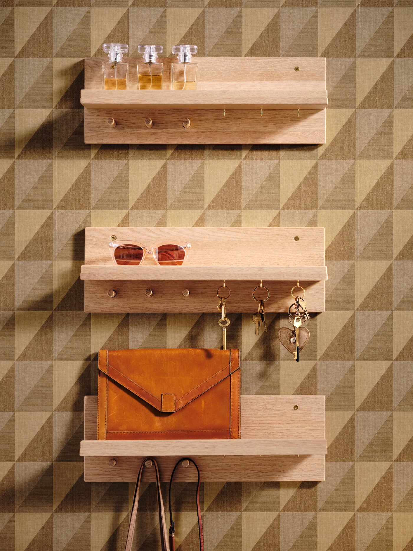 Trei organizatoare HÄSTVISKARE cu accesorii asortate montate în paralel, la înălțimi diferite, pe un perete cu model.