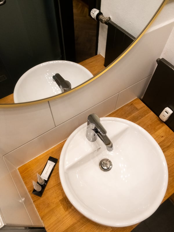 Ein goldener LINDBYN Spiegel und ein weißes Waschbecken bon oben.