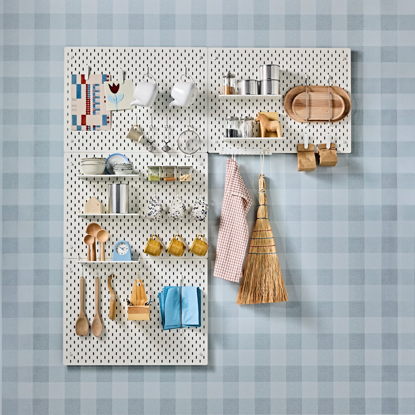 A kitchen wall featuring four SKÅDIS pegboards with utensils, mugs, teapots, and other items organised for easy access.