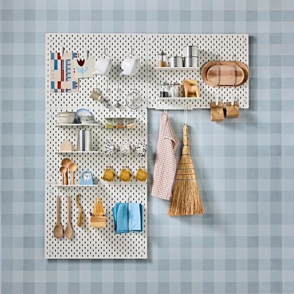 A kitchen wall featuring four SKÅDIS pegboards with utensils, mugs, teapots, and other items organised for easy access.